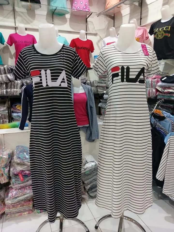 Bagian dalam toko: rak penuh kaos anak dan dress salur di manekin
